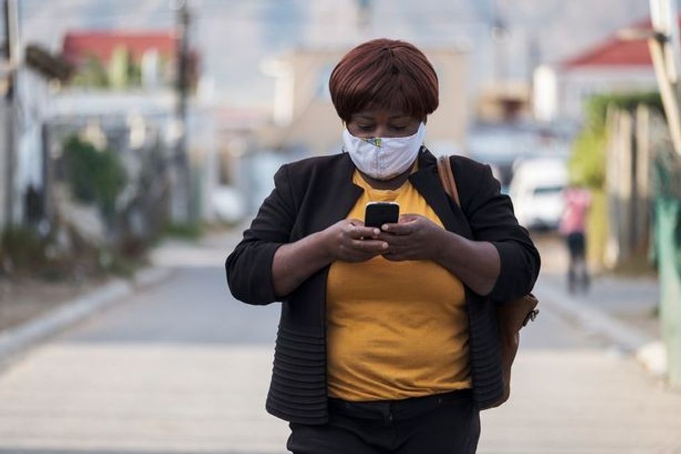0 African woman with homemade facemask using mobile phone