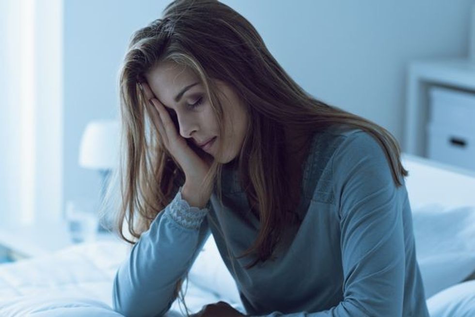 0 Depressed woman awake in the night she is touching her forehead and suffering from insomnia