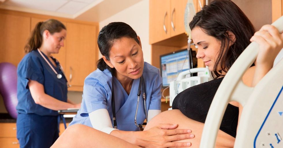 0 Doctor examining belly of pregnant woman