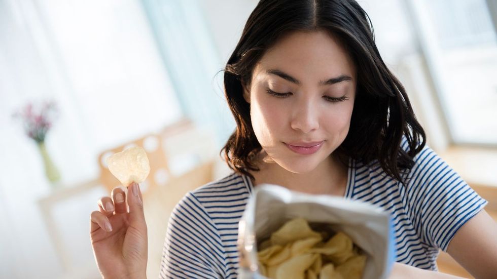 0 Hispanic woman reading ingredients on bag of potato chips