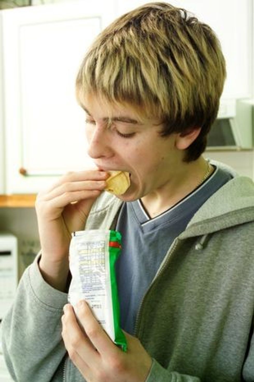0 Teenage boy eating crisps UK