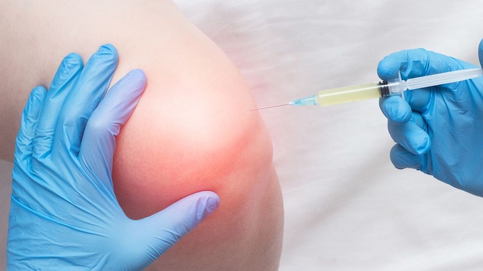 0 The doctor injects plasma into a sore inflamed female knee for arthrosis and arthritis plasma lift