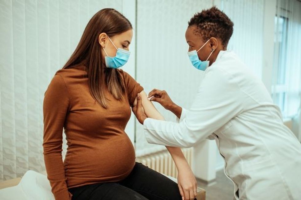 1 African American female doctor preparing a pregnant woman for vaccination