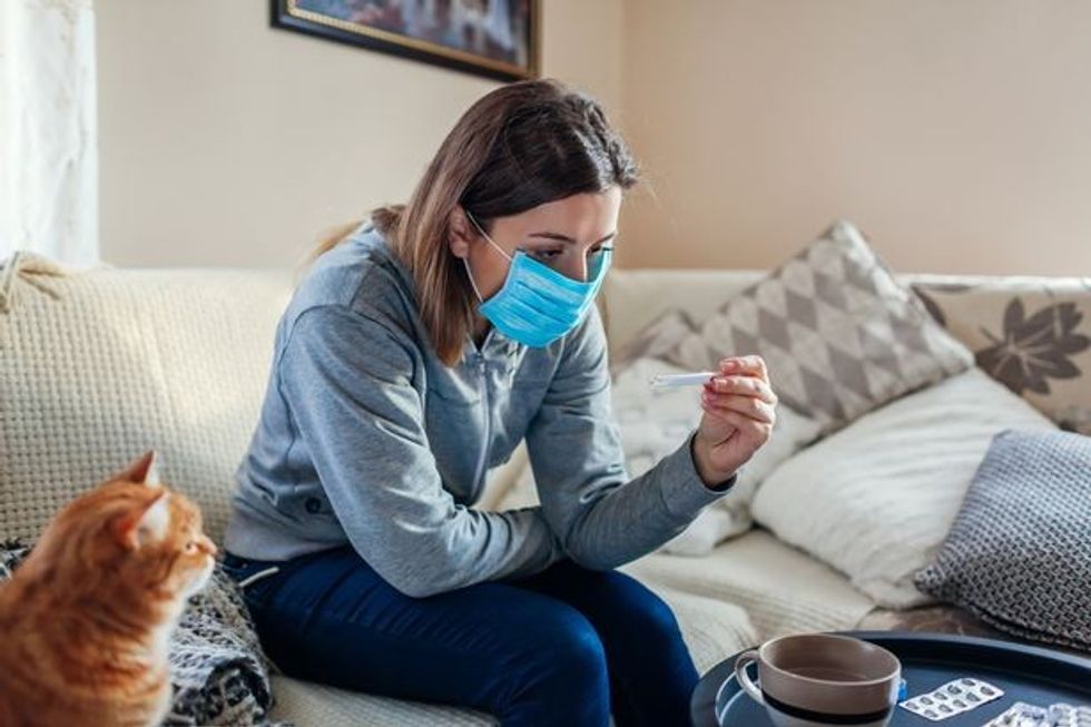 1 Ill woman checking thermometer having fever Girl wearing protective mask while having cold flu at