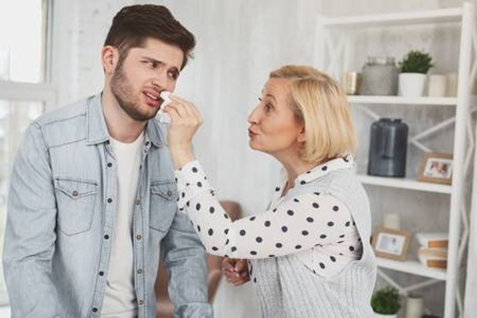 101338933 overcaring mother nice aged woman smiling while wiping her sins nose