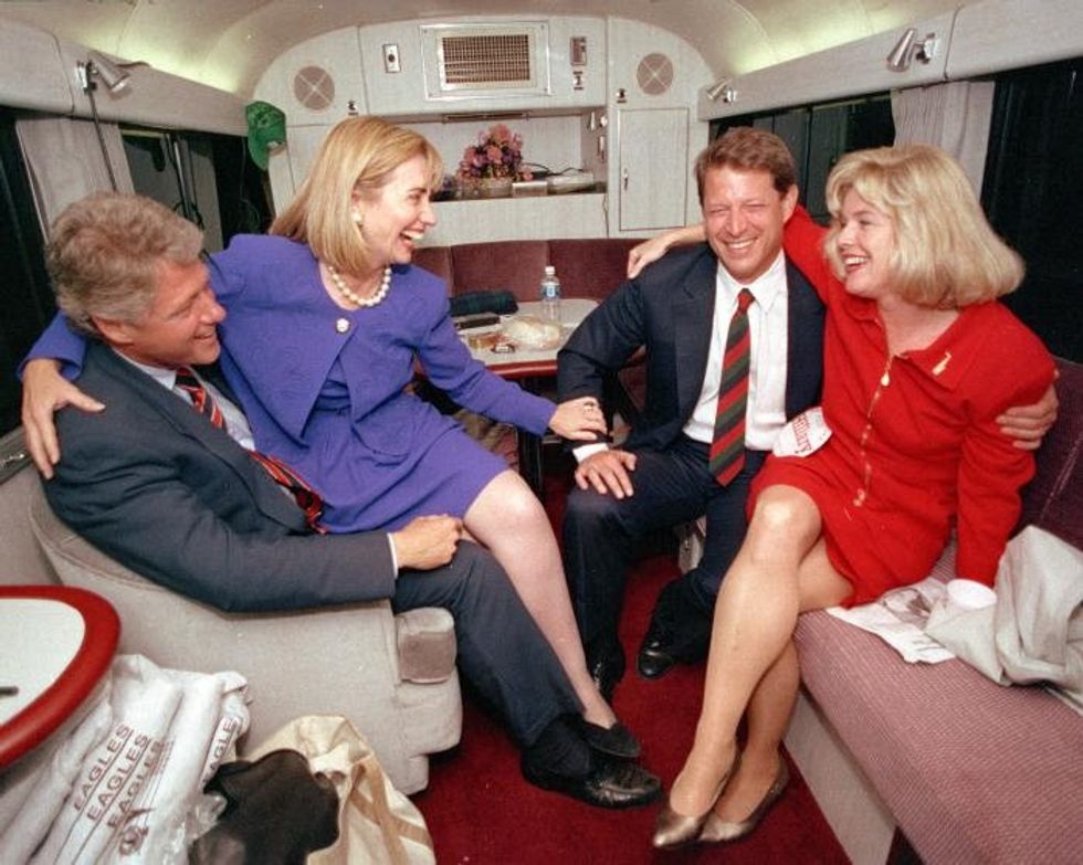 1992 Hillary Rodham Clinton sits on the lap of her husband, democratic presidential candidate Bill Clinton left, as she jokes with vice presidential candidate Al Gore and his wife, Tipper, during a brief rest on their bus in Durham, N.C., Monday, Oct. 26, 1992. The democratic ticket has spent the last two days touring the state. (AP Photo/Stephan Savoia)