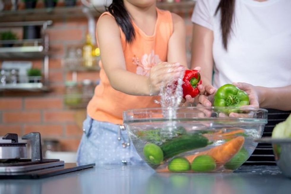 2 Hands of family washing fresh vegetables