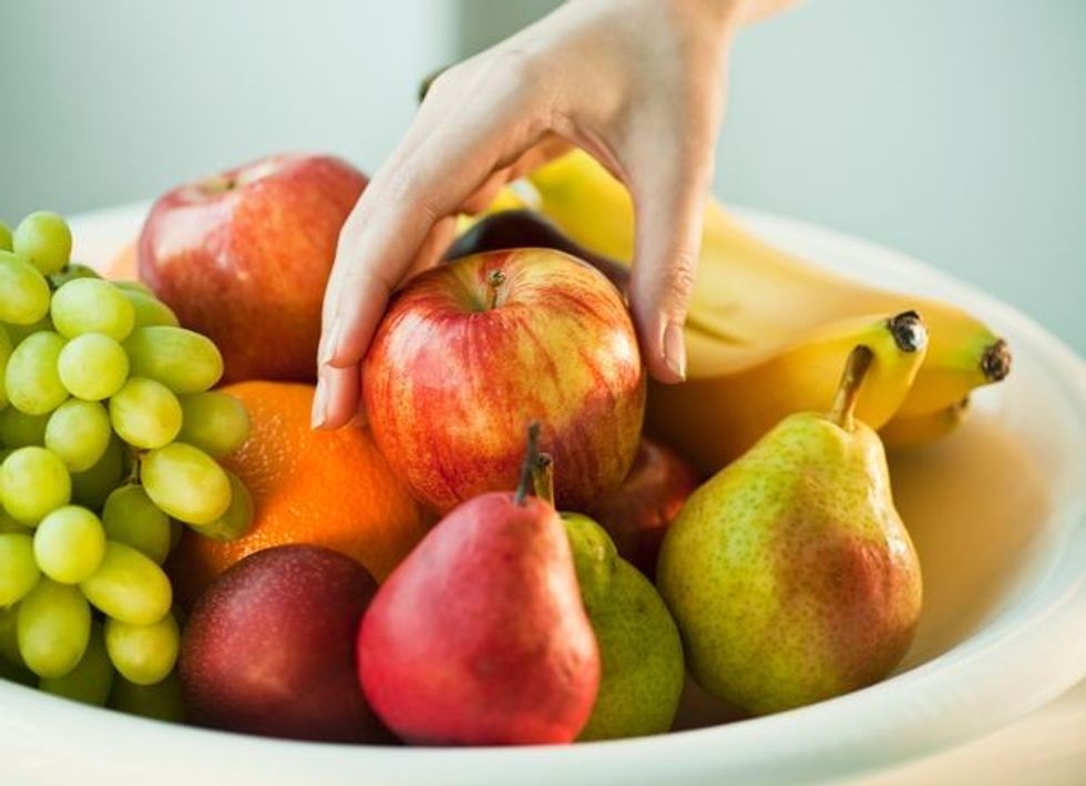 2 Womans hand taking apple from fruit bowl