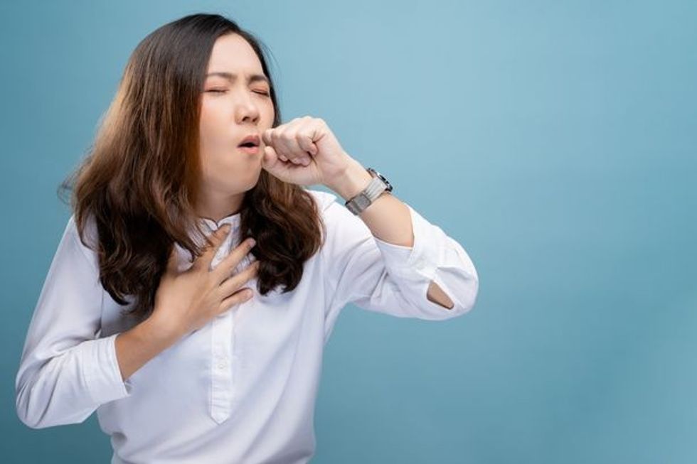 2 Young Woman Coughing While Standing Against Blue Background