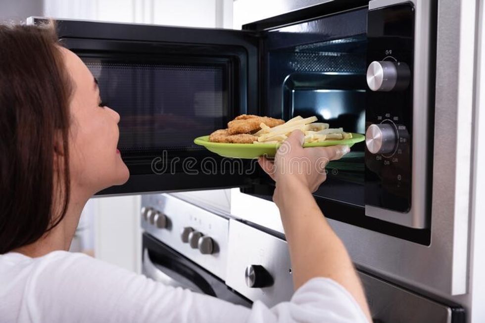2017/01/woman-heating-fried-food-microwave-oven-close-up-young-181275133.jpg