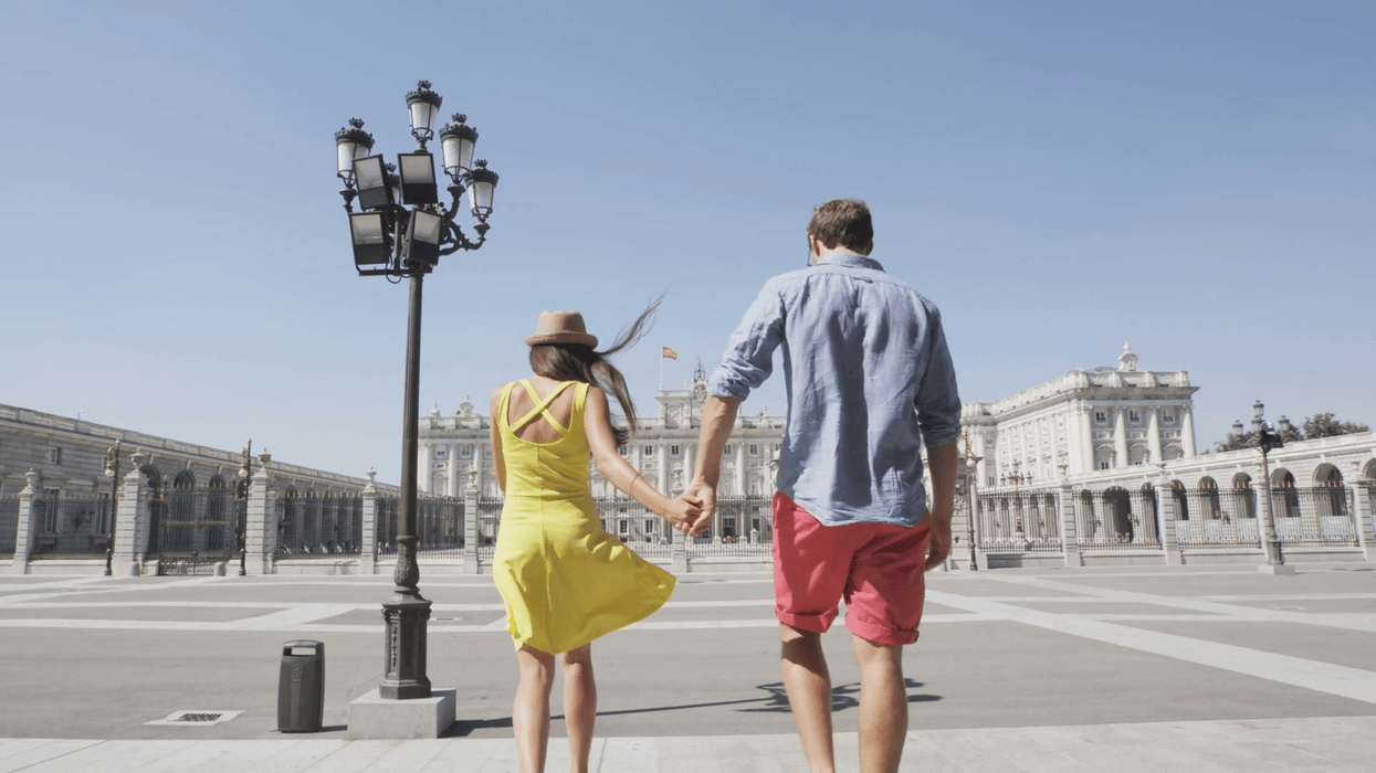 2018/04/young-couple-walking-holding-hands-happy-and-romantic-in-front-of-royal-palace-of-madrid-spain-tourists-traveling-in-europe-visiting-sp.png