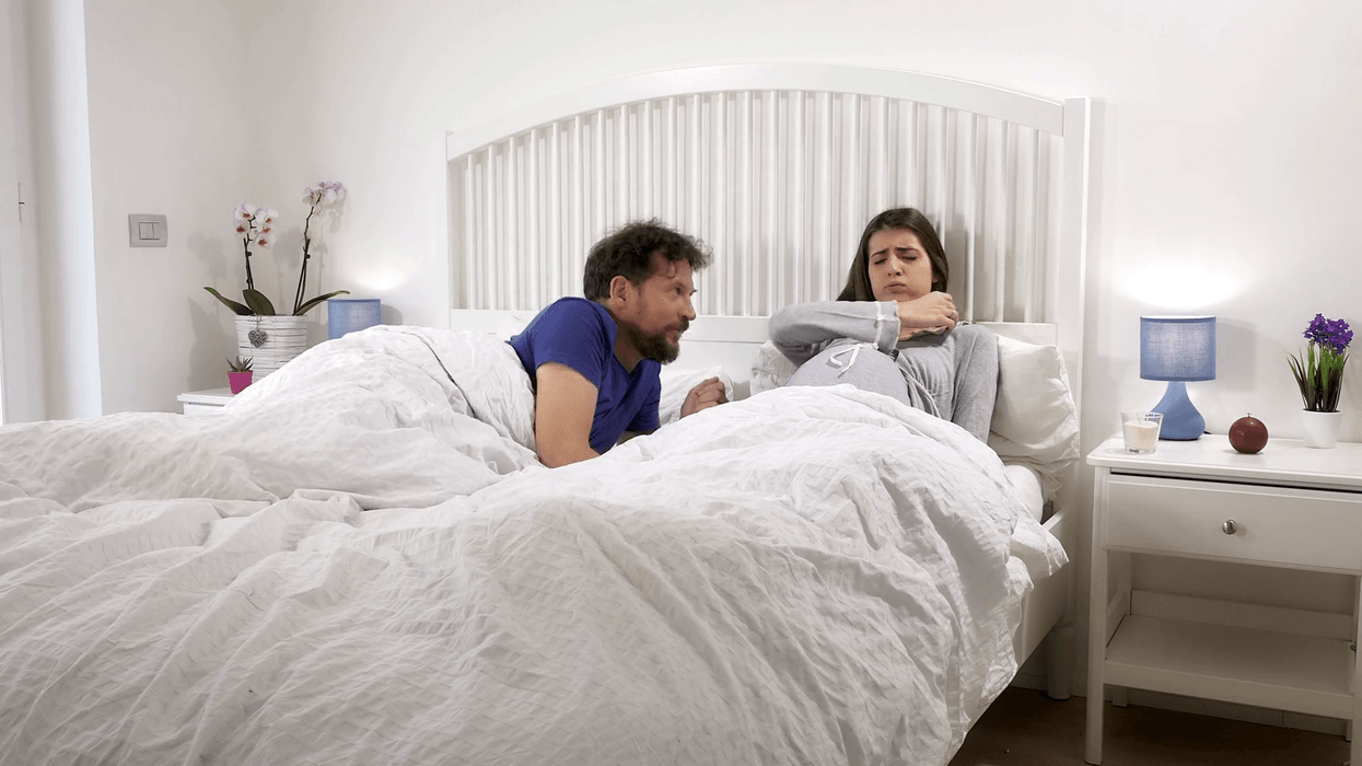 2018/07/videoblocks-annoyed-pregnant-woman-in-bed-with-husband-trying-to-help-her-to-feel-comf.png