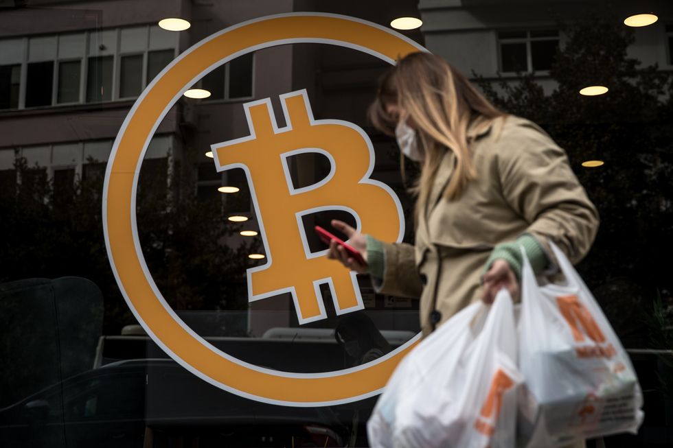 2021/04/woman-walks-past-bitcoin-sign-e1619252151144.jpg