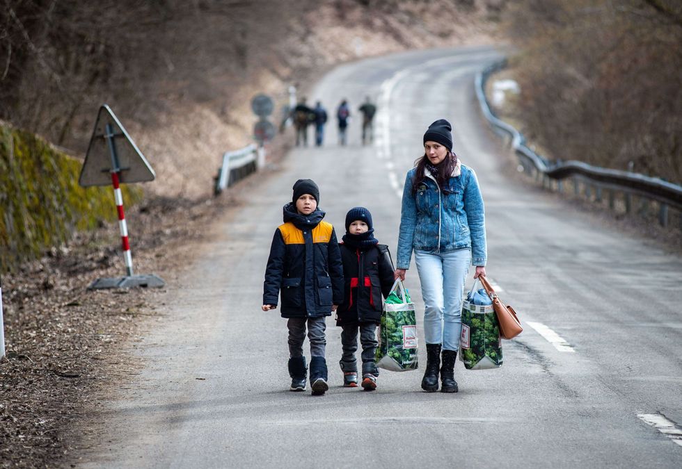 2022/03/woman-with-two-children-and-carrying-bags-walk-on-a-street-news-photo-1646060392-scaled.jpg