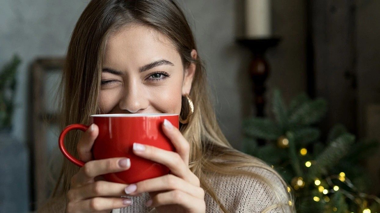 2024/12/a-woman-winks-while-drinking-from-a-mug.jpg