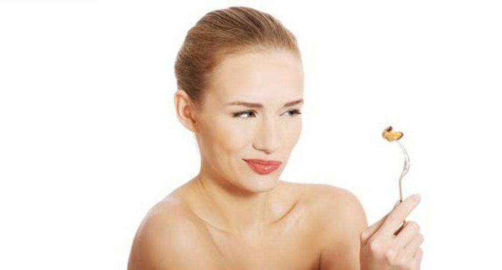 28887065 smiling caucasian woman eating sea fruit with fork isolated on white