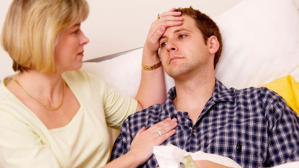 4 Woman checking young mans temperature in bed