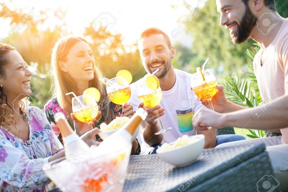 85465693 group of friends cheering with summer cocktails