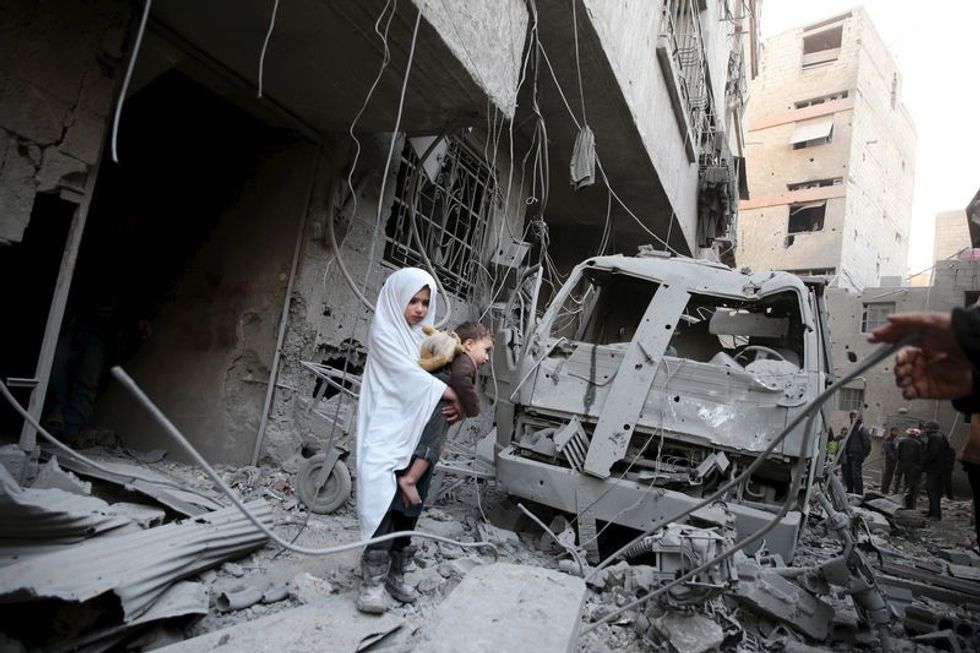 a girl carrying a baby inspects damage in a site hit by what data