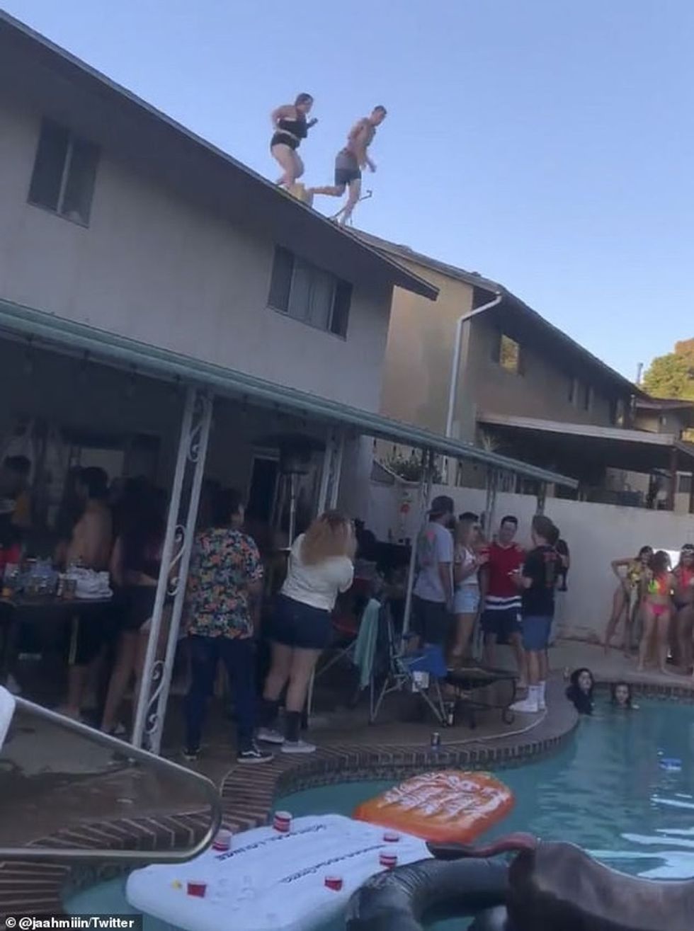 A man and woman prepared to jump off the roof of a home and into a pool