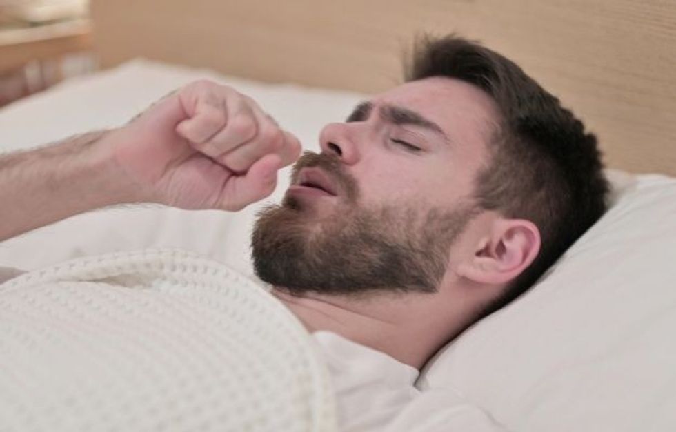 a man lying on bed and coughing ca