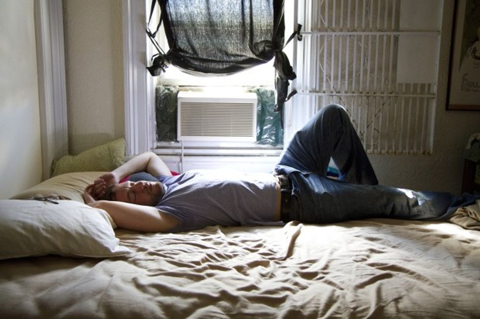 A man reclining on a unmade bed.