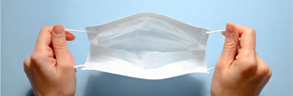 A woman holding face mask over blue textured table background