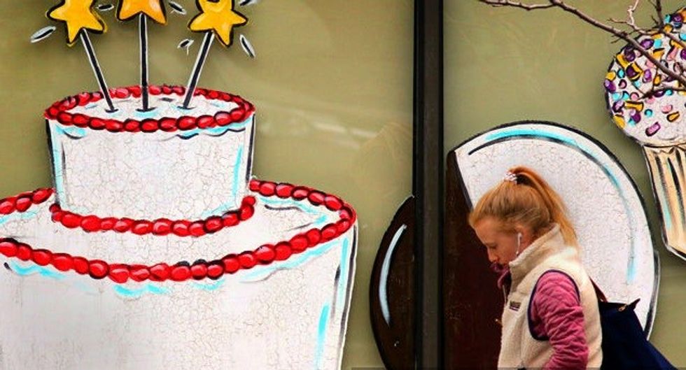 a woman passes a festive storefront with a bir
