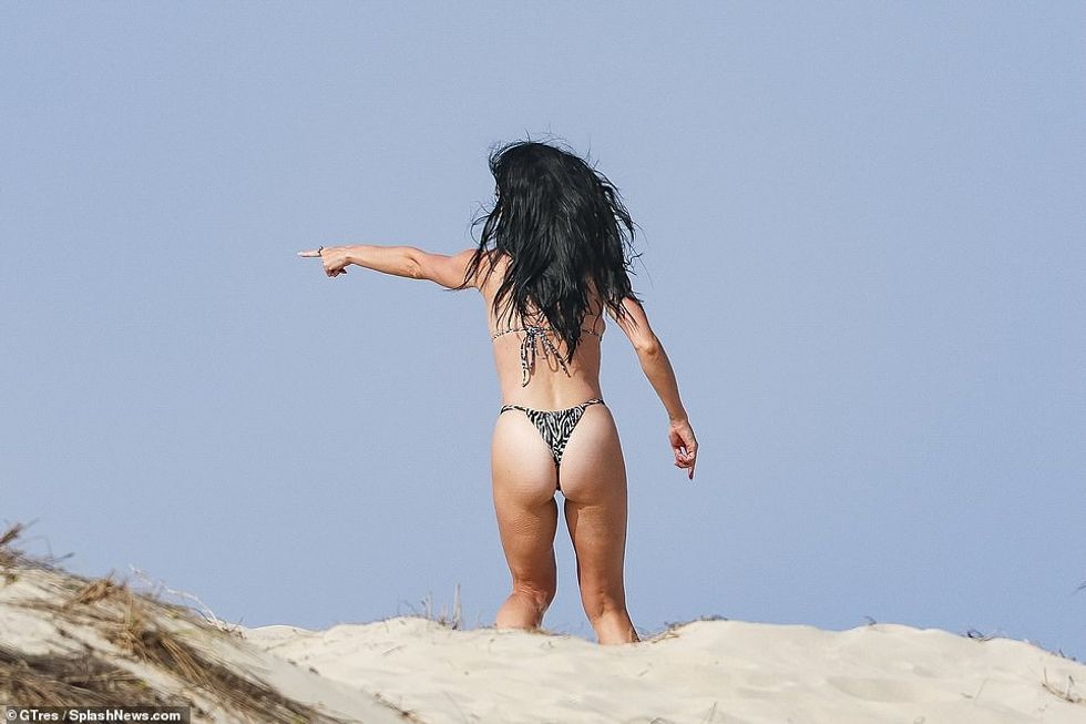 Ajo tregoi pjesën e pasme të saj me rroba banje të pakta