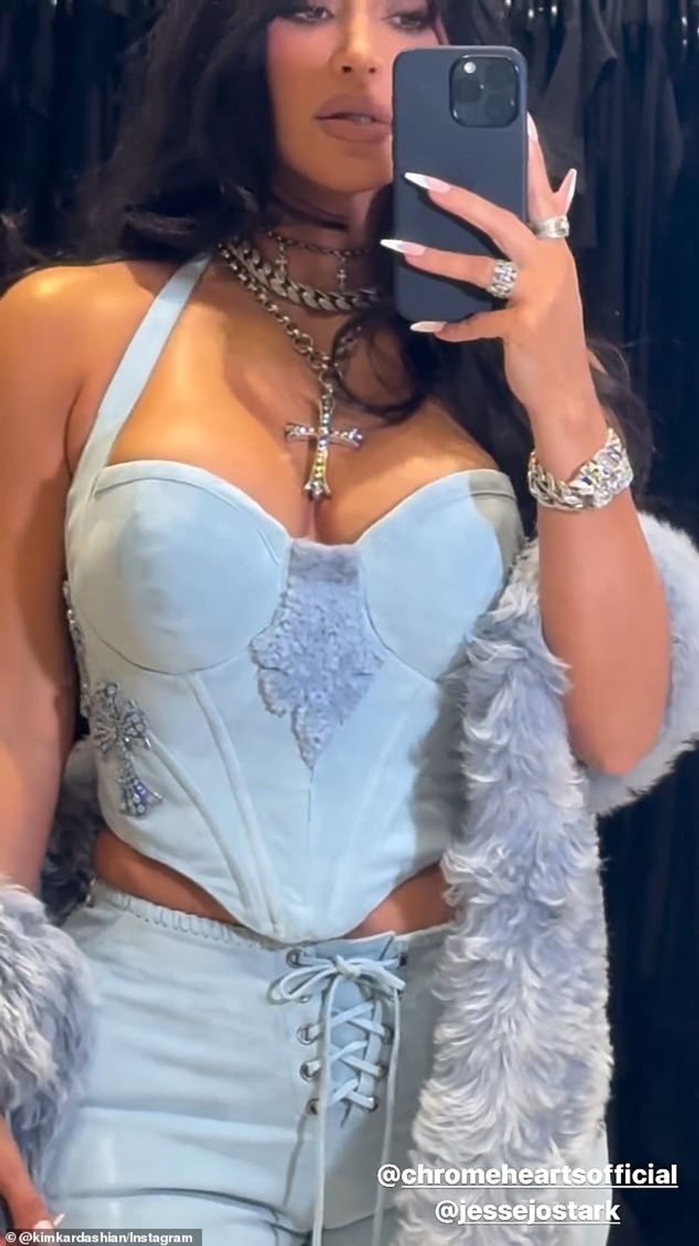 Ajo veshi një bluzë të çelët korse xhins me zbukurime vezulluese në formë kryqi në secilën anë