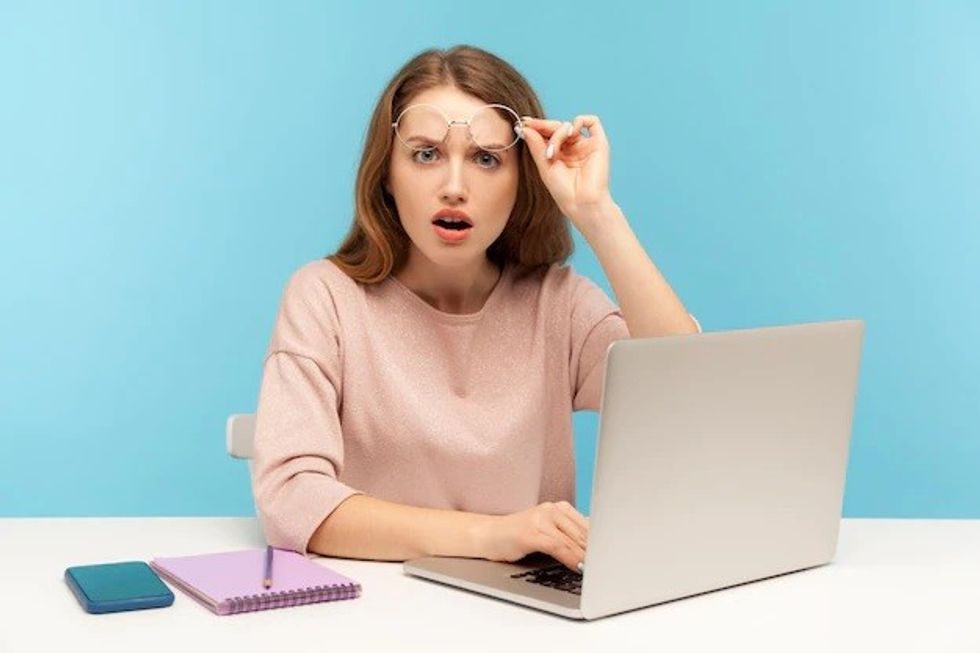 astonished smart woman taking off eyeglasses looking with open mouth amazement