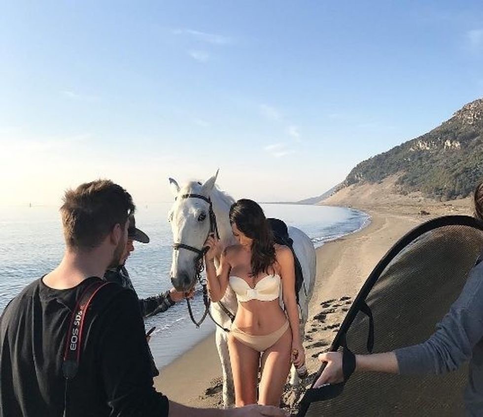 Aurela Hoxha shfaqet me bikini pranë një kali të bardhë në bregdet. Xhirime të realizuara tek