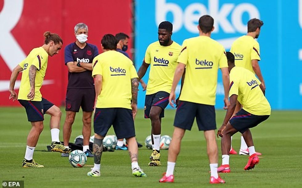 Barcelona manager Quique Setien wears a mask as he watches over his players in training