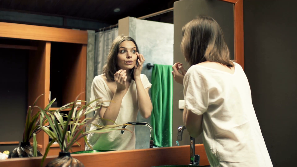 beautiful woman checking her face in the mirror in bathroom vkmp5vfgx F0000