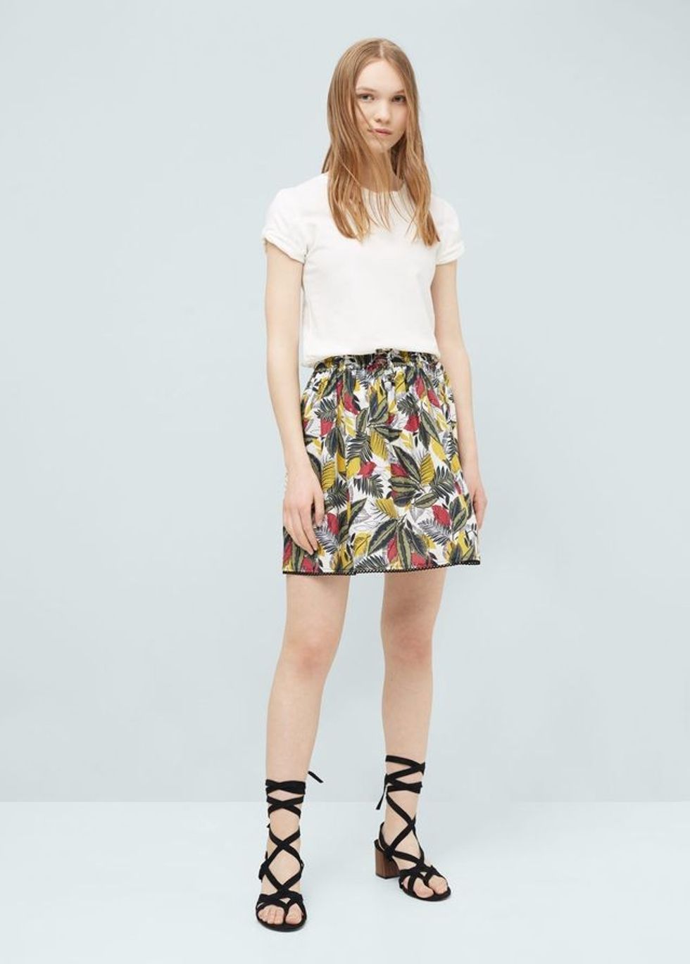 Bluzë e bardhë me mëngë të shkurtra, fund me motive dhe sandale gladiatori.