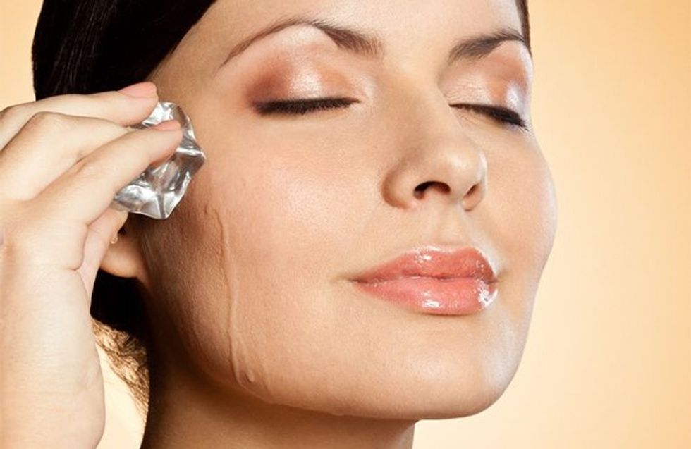 brunette woman holding ice cube on her face, closeup portrait