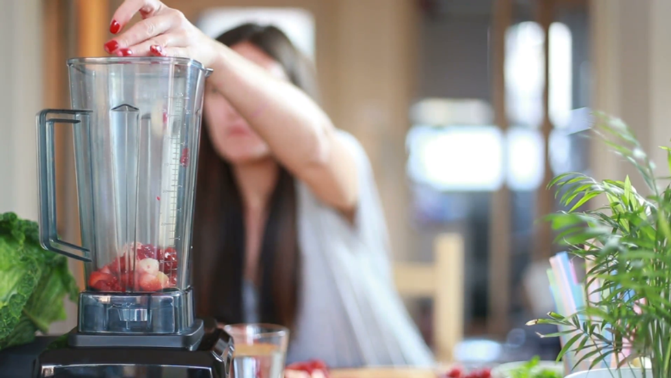 brunette woman putting fruits in blender for blending 42lycvx dg F0012
