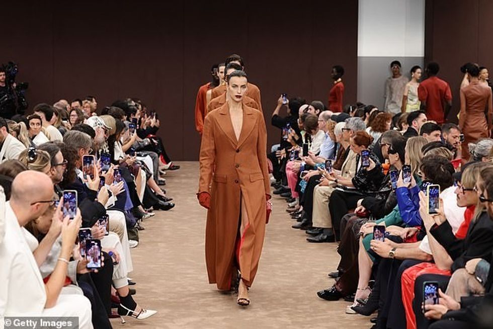 Bukuroshja hodhi një vështrim të shkurtër të këmbëve të saj të tonifikuara poshtë palltos, e cila ishte e pajisur me doreza lëkure kafe, një tufë kuti dhe taka të zeza me xhufka.