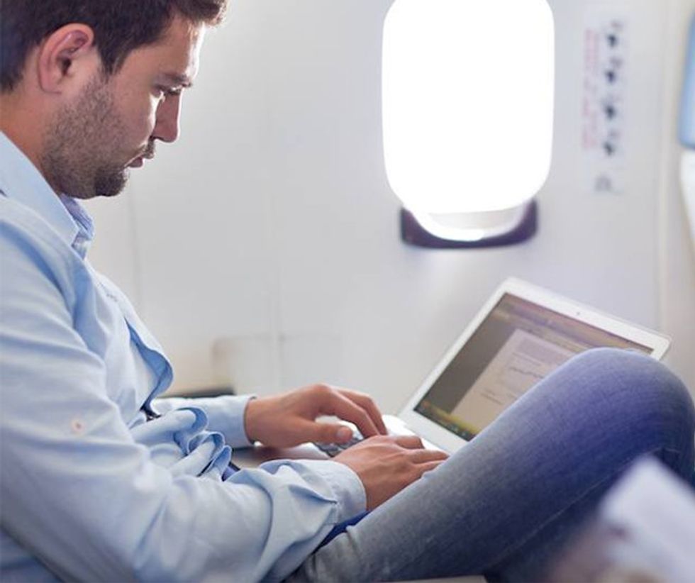 Businessman working with laptop on airplane.
