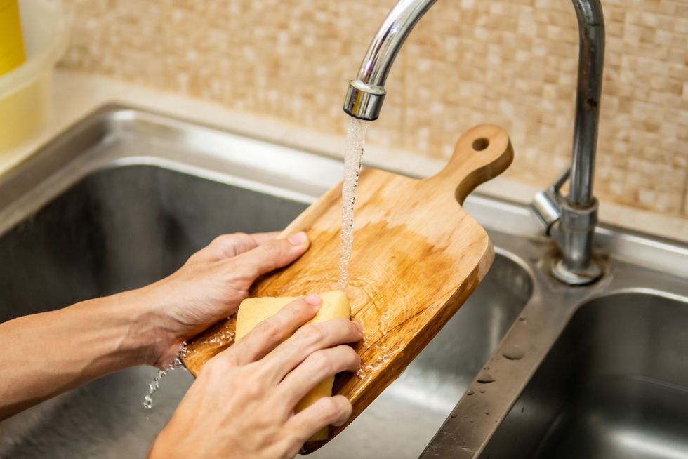 cleaning wood cutting board in kitchen sink royalty free image 1583340534 scaled