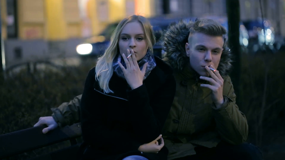 couple sitting at night on the bench and smoking cigarettes nyg4itef F0000