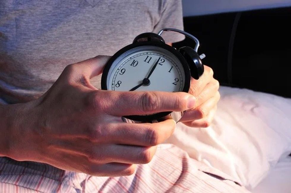 depositphotos 69952325 young man in bed setting the alarm clock