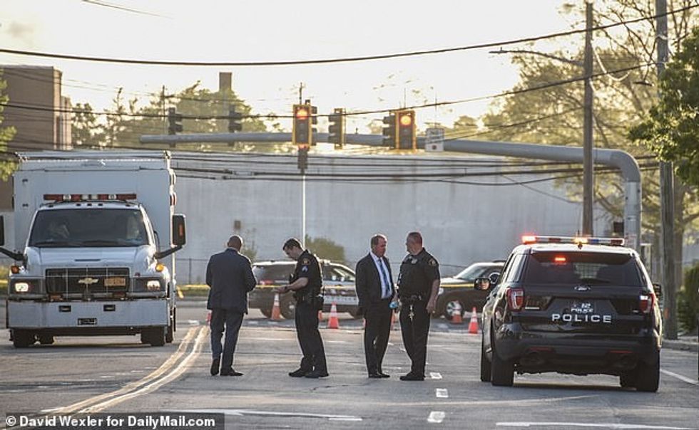 Detectives and officers stand in a street closure during their investigation of the stabbing