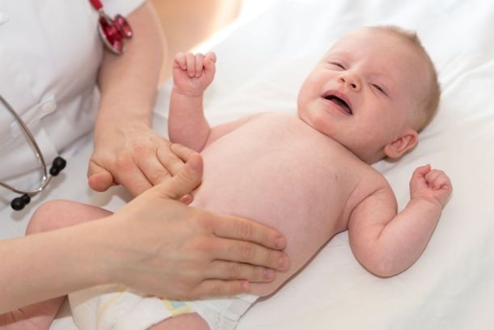 Doctor pediatrician examining baby tummy in clinic
