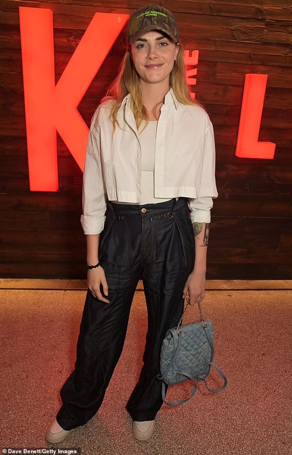 Duke festuar shfaqjen, Cara, e cila identifikohet si queer dhe panseksuale, ka një trup elegant në modë, një palë pantallona të zeza të gjera, një këmishë të bardhë të shkurtër dhe atlete.