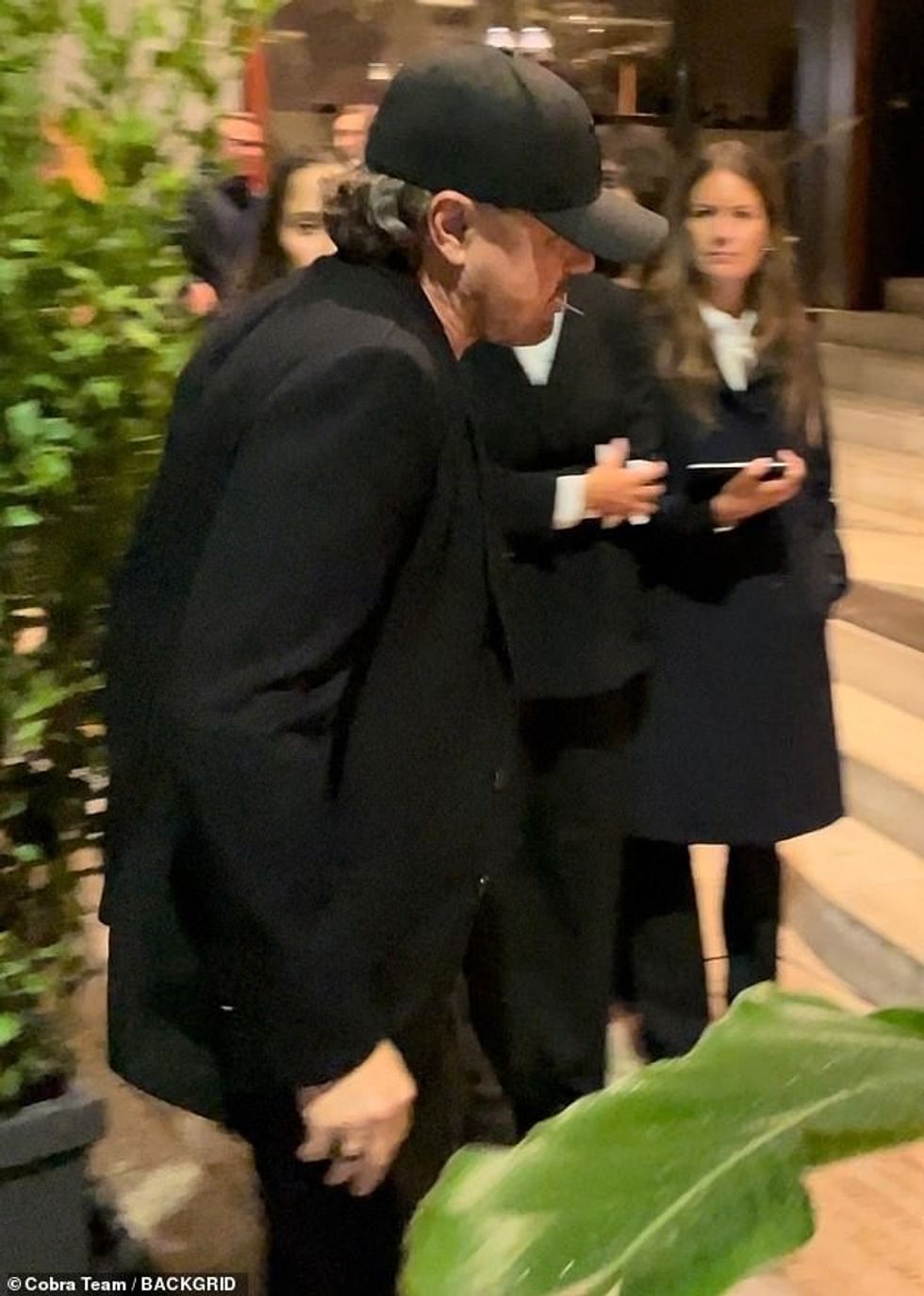 Duke shtuar një nuancë rastësie në pamjen e tij, ai u pa duke përtypur një kruese dhëmbësh ndërsa ngjitej në shkallët e restorantit