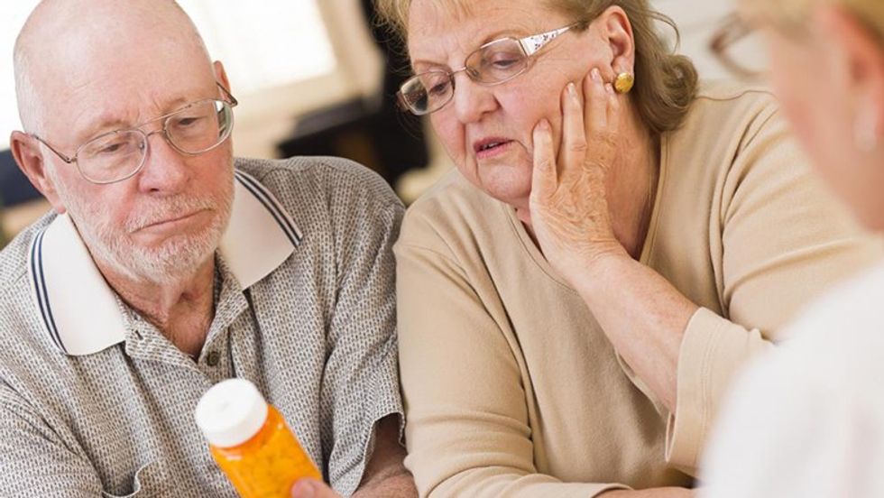 elderly couple looking at bottle of medicine