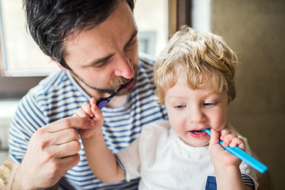 father brushing his teeth with a toddler boy at PCN5QMT 1
