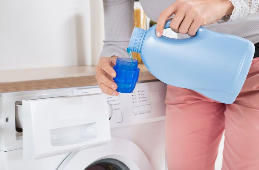 female hands pouring detergent in the bottle cap 511027756 5a938428875db90036