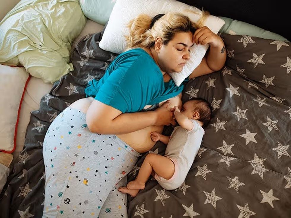 female mother breastfeeding bed